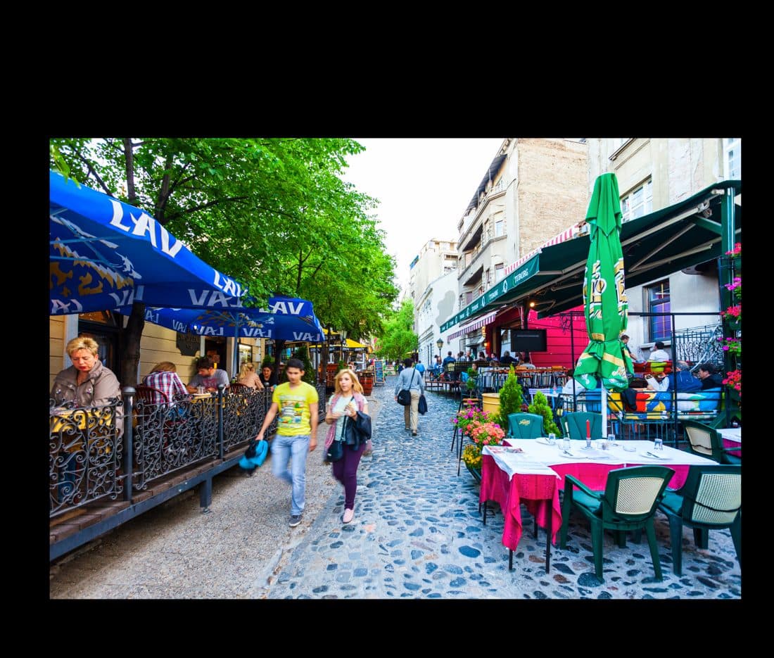A lively main-street cafe with people gathered at outdoor tables