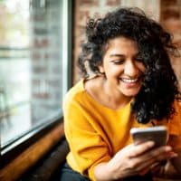 Early pilot member smiling at her phone in a cafe