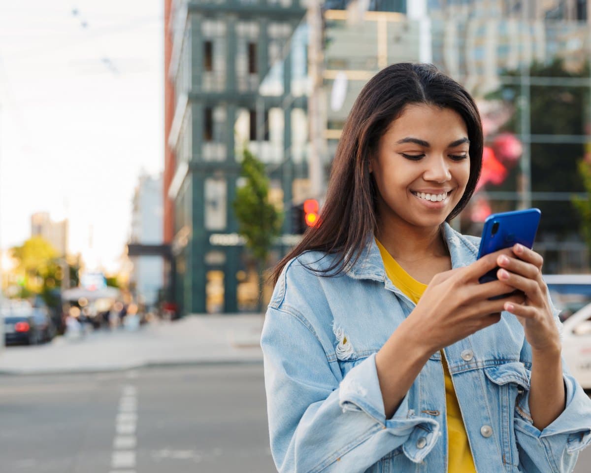 A woman checking the GeoMine map on her phone while out on a sunny city street