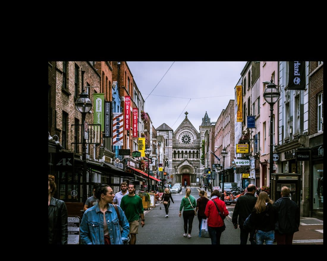 People walking along a busy local main street lined with shops